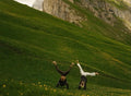 Two people upside down on a green mountain hillside