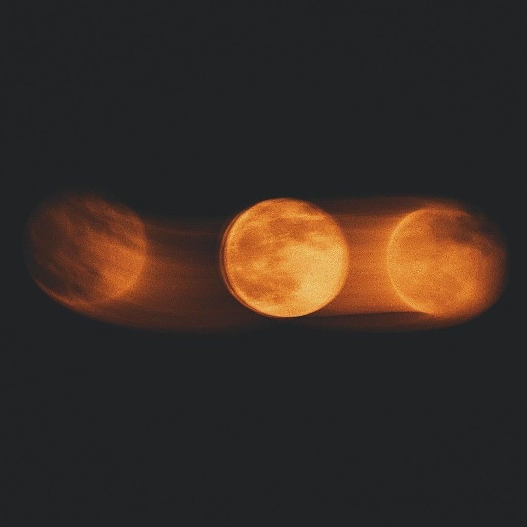 Three amber moons against a dark sky