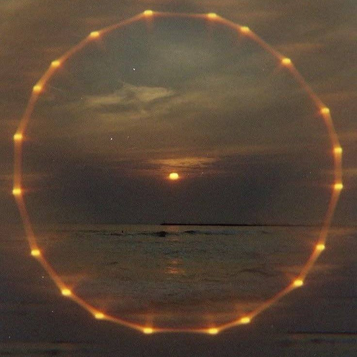A ring of amber light over the sea at dusk